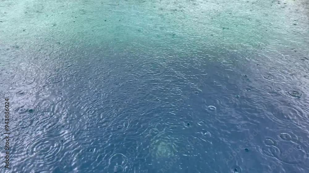 Rain drops falling onto the surface of a swimming pool, rain pours water into the pool, Rain droplets drops falling onto the surface of a swimming pool Rain drops falling onto the surface of a swimming pool, rain pours water into the pool, Rain droplets drops falling onto the surface of a swimming pool