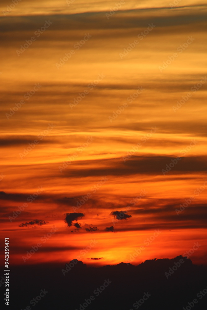 Fototapeta premium The sun setting behind the clouds. Orange sky. Amazing sunset