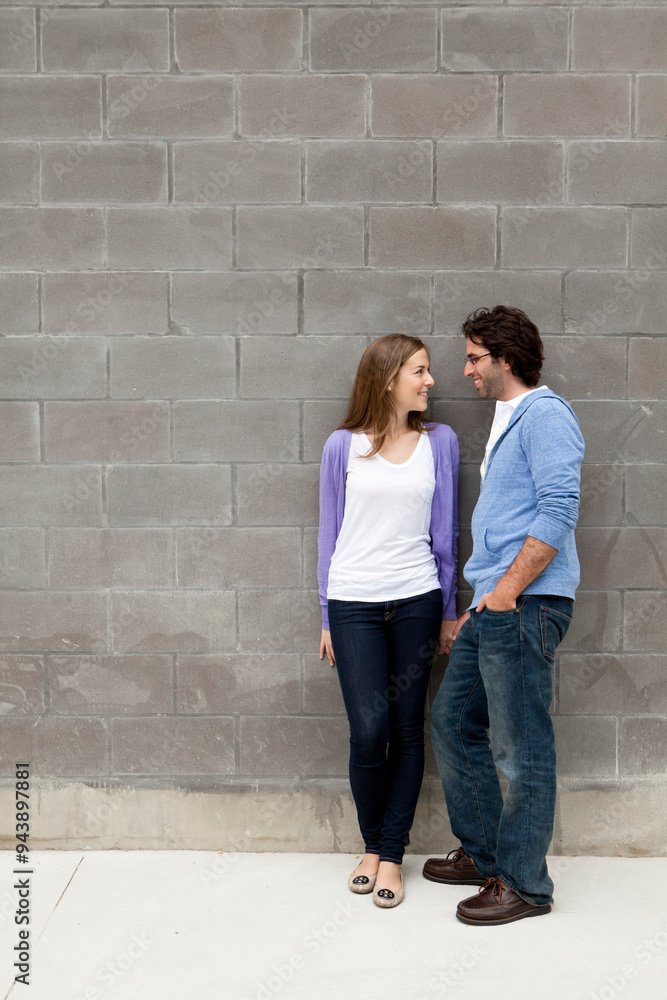 Young Couple Standing in front of Stone Wall Young Couple Standing in front of Stone Wall