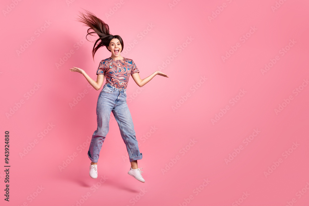 Full length photo of adorable lovely girl wear retro t-shirt jumping high hair flying emtpy space isolated pink color background Full length photo of adorable lovely girl wear retro t-shirt jumping high hair flying emtpy space isolated pink color background