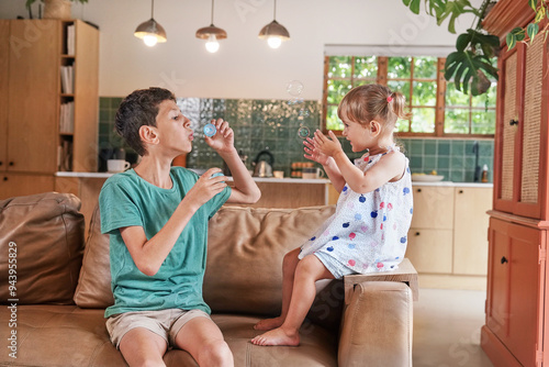 Brother (8-9) and sister (18 - 23 months) blowing bubbles at home photo