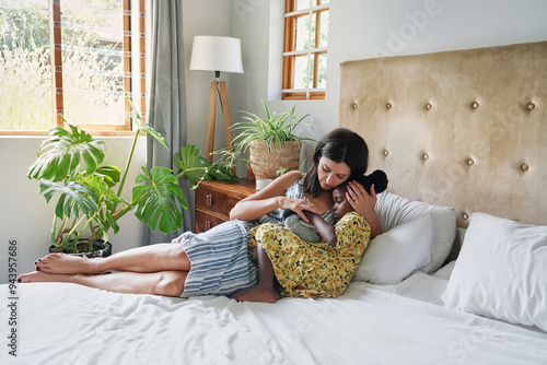 Mother hugging daughter (6-7) on bed photo