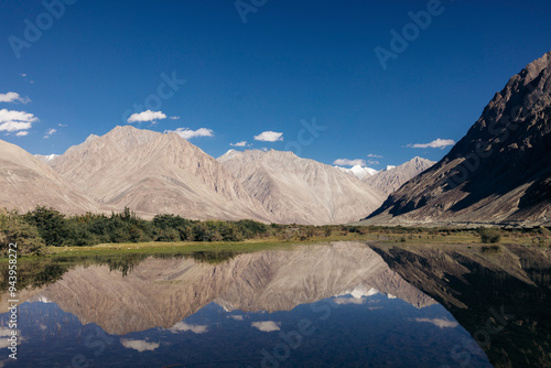 Mountains reflected in mirror image in water in the Nubra Valley; Leh, Ladakh, India