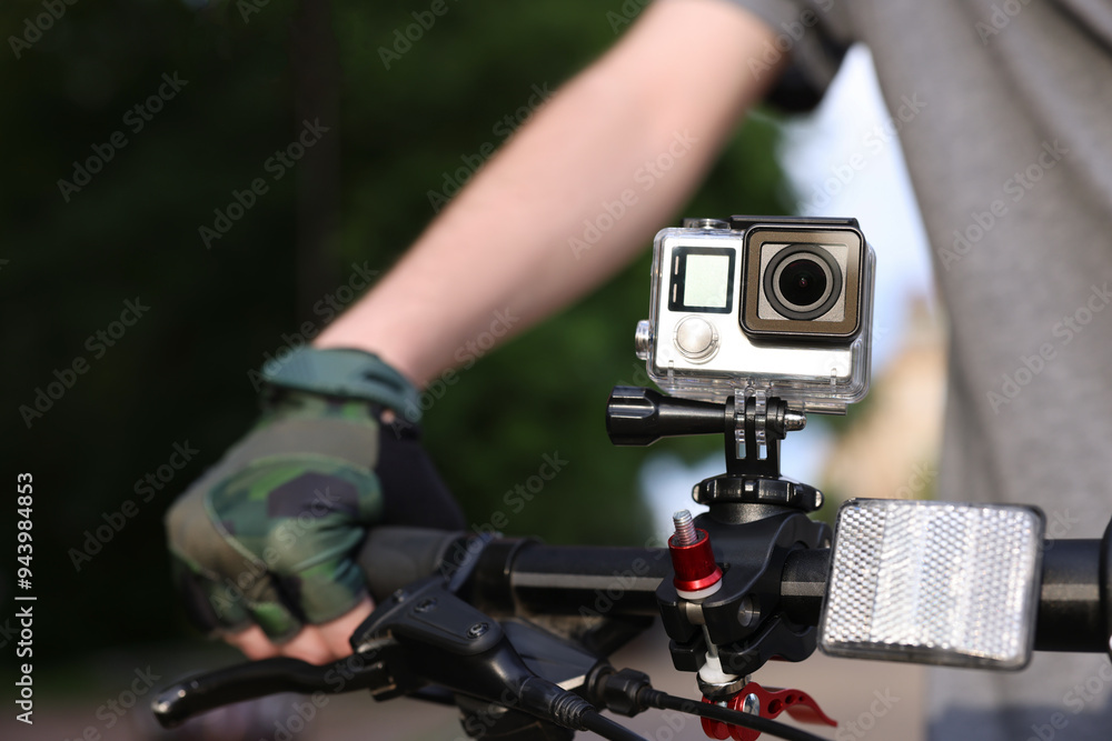 Man riding bicycle with modern action camera outdoors, closeup Man riding bicycle with modern action camera outdoors, closeup