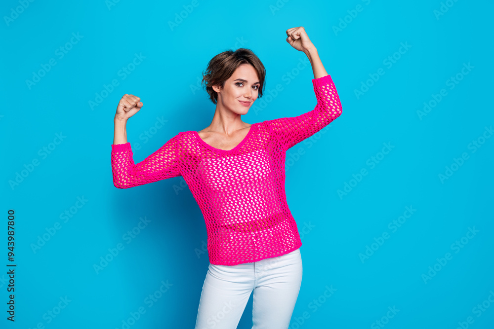 Photo of pretty strong woman wear knitted neon shirt rising fists showing muscles isolated blue color background Photo of pretty strong woman wear knitted neon shirt rising fists showing muscles isolated blue color background
