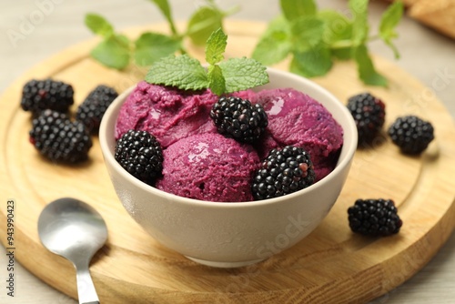 Delicious blackberry sorbet with fresh berries in bowl and spoon on table, closeup