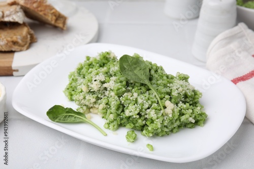 Delicious spinach risotto with parmesan cheese on white tiled table, closeup