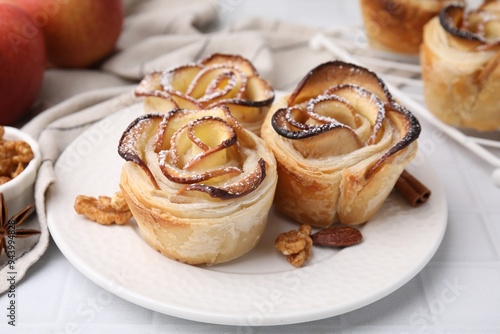 Freshly baked apple roses and walnuts on white tiled table, closeup. Puff pastry