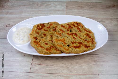 Potato Stuffed Flat Bread or Aloo paratha is a Traditional Indian food. served with curd, butter or ghee. selective focus. isolated on yellow background. photo