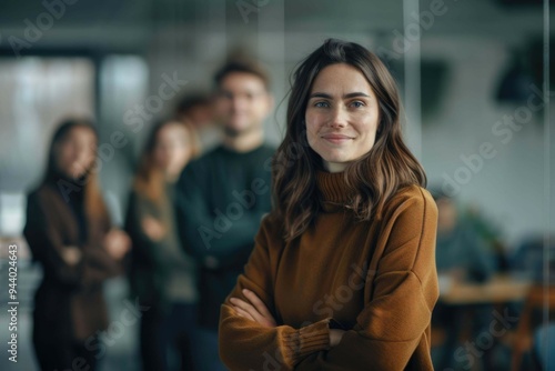 Successful businesswoman standing in creative office and looking at camera while smiling. Portrait of beautiful business woman standing in front of business team at modern agency with copy space.