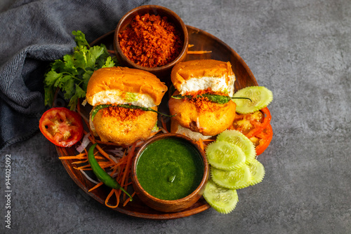 selective focus of Mumbai's famous street food delicious Vada Pav, With coriander leave chutney, tomato sauce, dry garlic chutney and fried chilli.  photo