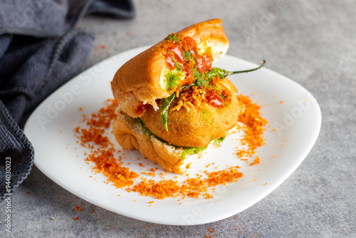 selective focus of Mumbai's famous street food delicious Vada Pav, With coriander leave chutney, tomato sauce, dry garlic chutney and fried chilli.  photo