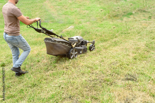 man cutting the grass with black lawnmower