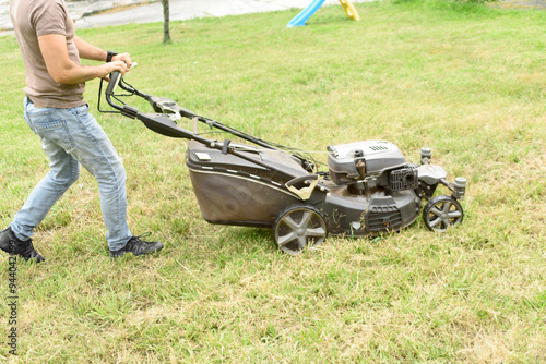 man cutting the grass with black lawnmower