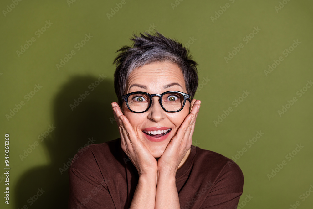 Photo portrait of gray hair beautiful grandmother in brown t shirt and eyeglasses touch cheeks amazing news isolated on khaki color background Photo portrait of gray hair beautiful grandmother in brown t shirt and eyeglasses touch cheeks amazing news isolated on khaki color background