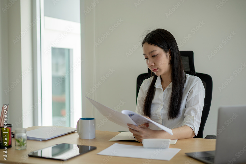 A woman is sitting at a desk with a white shirt and black chair A woman is sitting at a desk with a white shirt and black chair