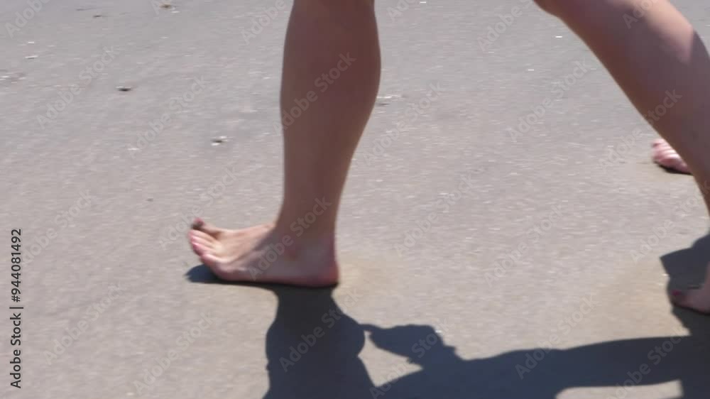 Slow motion close up of feet walking across a beach on a sunny day. Slow motion close up of feet walking across a beach on a sunny day.