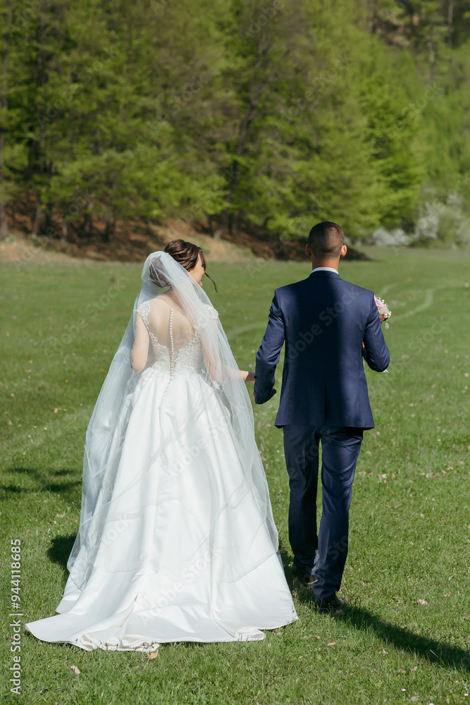 A bride and groom are walking together in a field. The bride is wearing a white dress and a veil, while the groom is wearing a blue suit. The scene is peaceful and romantic A bride and groom are walking together in a field. The bride is wearing a white dress and a veil, while the groom is wearing a blue suit. The scene is peaceful and romantic