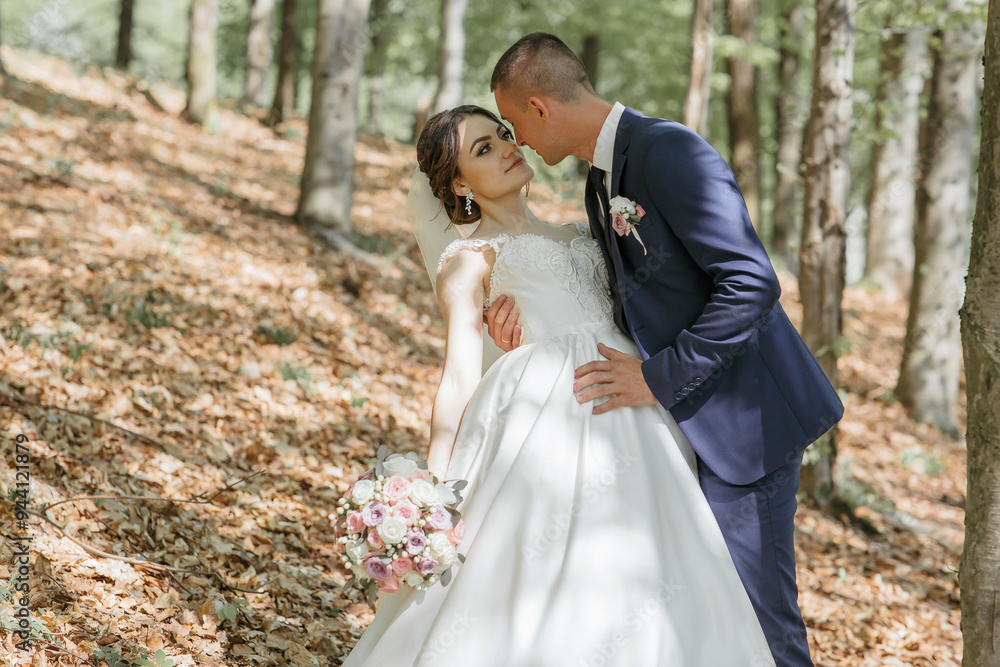 A bride and groom are standing in a forest, with the bride wearing a white dress and the groom wearing a blue suit A bride and groom are standing in a forest, with the bride wearing a white dress and the groom wearing a blue suit