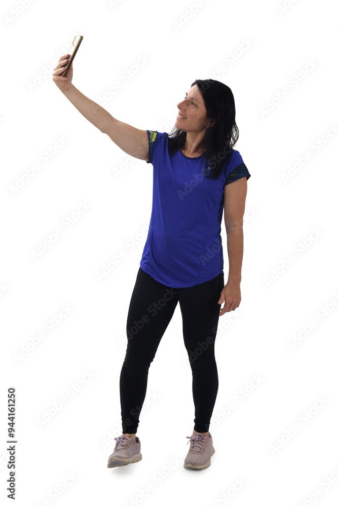 side view of a woman in sportswear with her arm raised making a self-portrait on white background