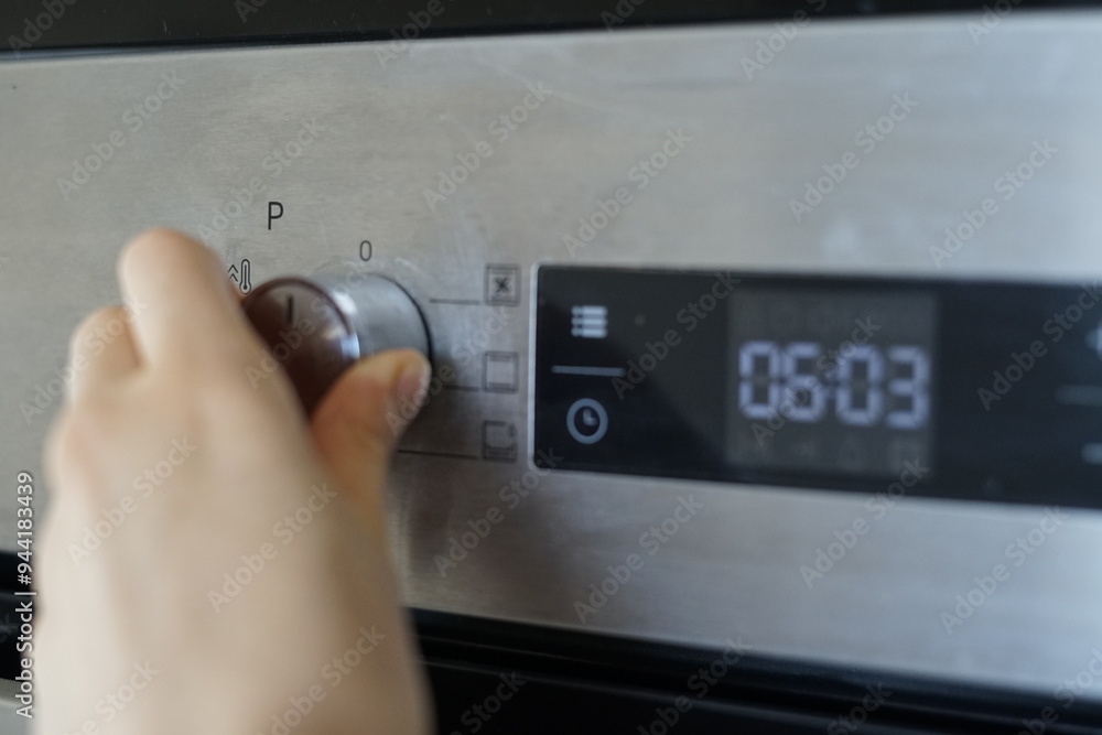 Woman hand set the oven temperature and mode, adjusting the settings to bake, roast, broil cooking Woman hand set the oven temperature and mode, adjusting the settings to bake, roast, broil cooking