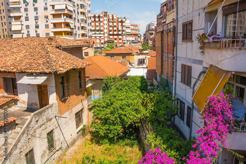 Housing with old and new contrasting architectural styles in the centre of Tirana, central Albania. In the centre is an overgrown courtyard with bougainvillea flowers #944220200