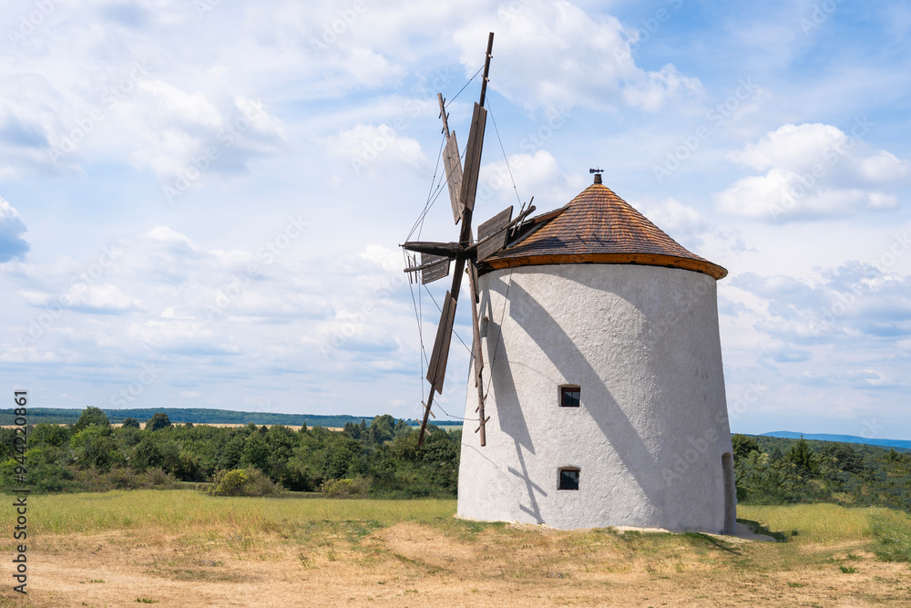 Old traditional windmill with cloudy blue sky in the background Old traditional windmill with cloudy blue sky in the background
