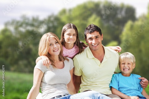 Cheerful young family sitting on the park.