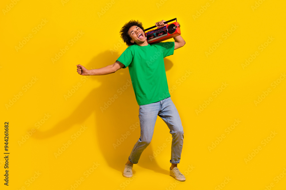 Full length photo of attractive funny guy wear green t-shirt enjoy boom box songs singing emtpy space isolated yellow color background Full length photo of attractive funny guy wear green t-shirt enjoy boom box songs singing emtpy space isolated yellow color background