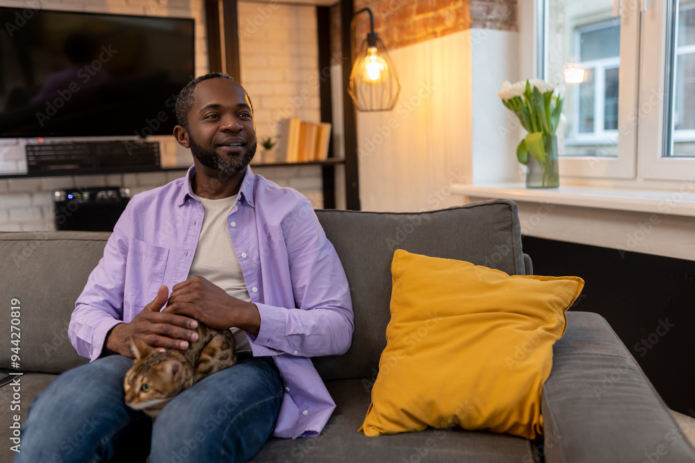 African american man sitting at home with a cat on his laps African american man sitting at home with a cat on his laps