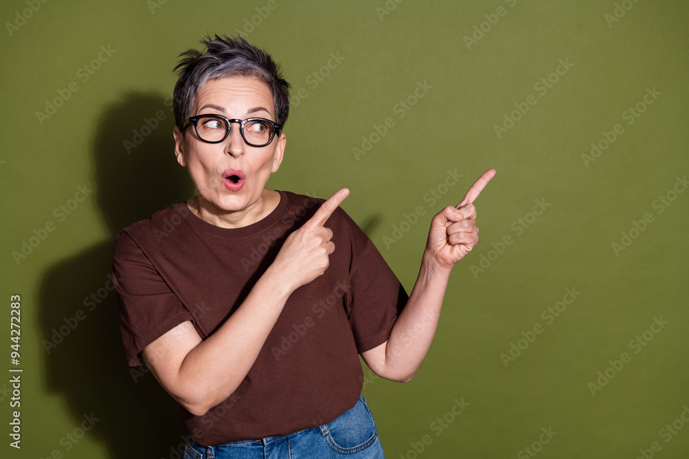 Photo portrait of attractive retired woman amazed point look empty space dressed stylish brown clothes isolated on khaki color background Photo portrait of attractive retired woman amazed point look empty space dressed stylish brown clothes isolated on khaki color background