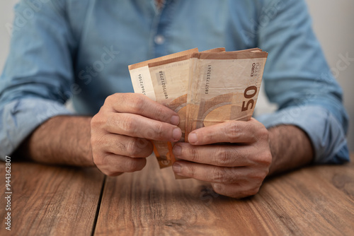 Man entrepreneur holds euro banknotes counting money with attention preparing cash for paying salary to workers in end of work shift sitting at workplace in office