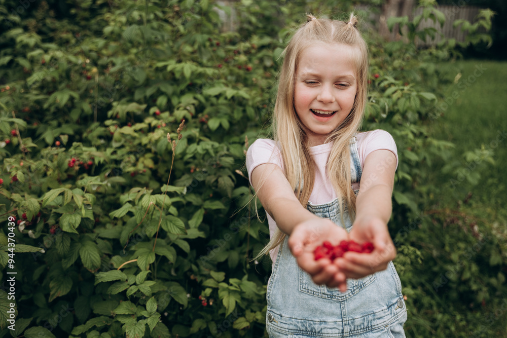 Smiling Little Blonde Girl Holding Fresh Raspberries Outdoors on a Summer Day Smiling Little Blonde Girl Holding Fresh Raspberries Outdoors on a Summer Day