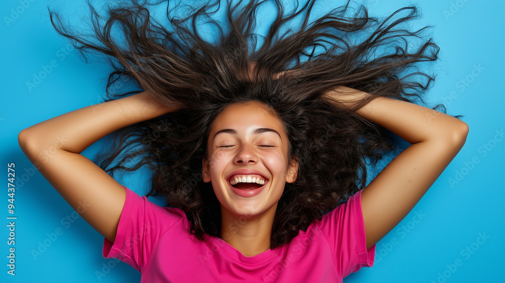 Portrait of 20s young woman laughing, wearing pink t-shirt on blue background Portrait of 20s young woman laughing, wearing pink t-shirt on blue background