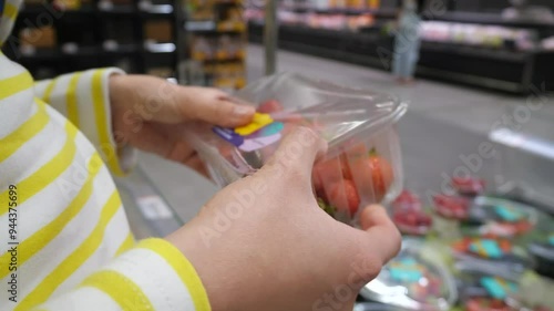 Shopper holding plastic bag of fresh strawberries in grocery store. Farm fresh fruits. photo