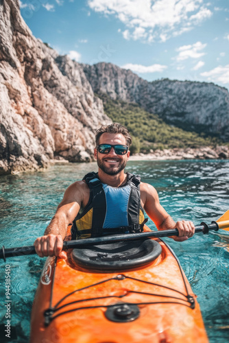 Portrait of a happy male in kayak boat exploring rocky valley in shallow sea photo