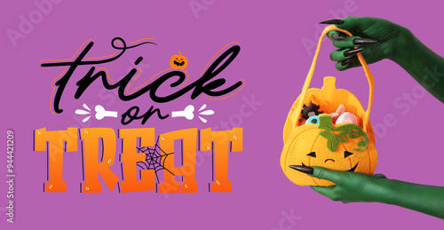 Green hands of witch with bag and candies on purple background. Halloween celebration