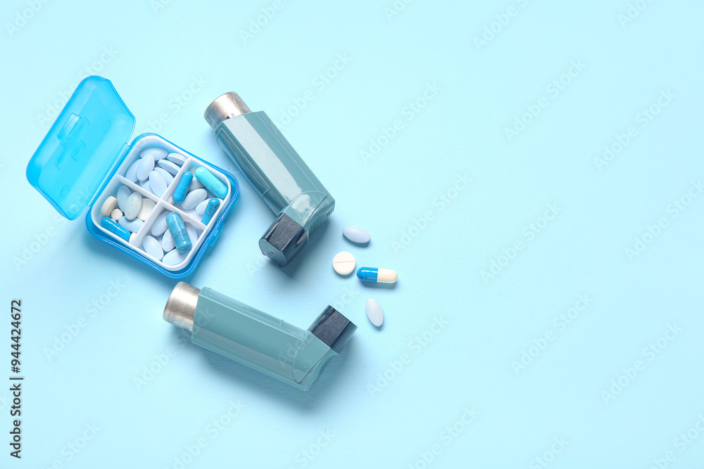 Fototapeta premium Asthma inhalers and box with pills on blue background