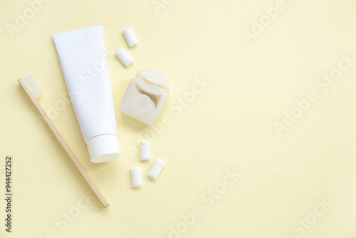 Fotografie Toothpaste with brush, dental floss and chewing gums on light yellow background