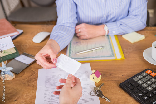 Real estate agent gives a business card to customer, marking a successful investment in business of property, whether it be a house or an apartment. Real estate agent giving house key to customers.