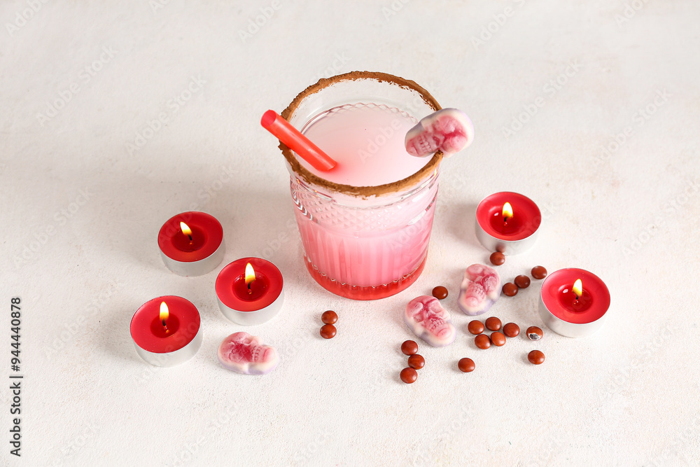 Φωτογραφία Glass of tasty Margarita cocktail, candles and candies for Halloween on light ba