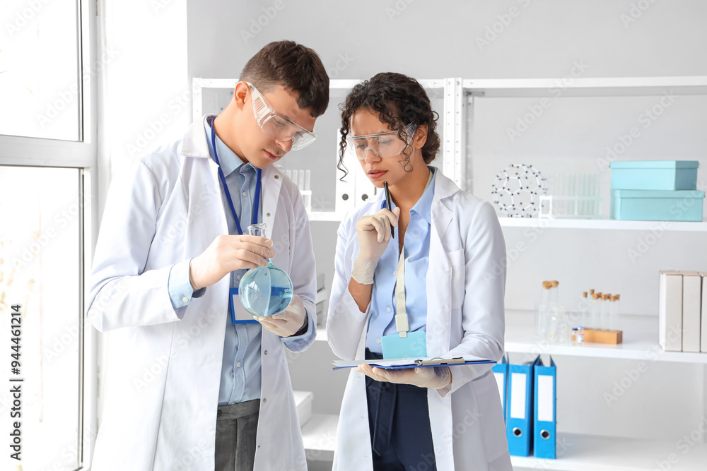 Young chemists with flask working in laboratory Young chemists with flask working in laboratory