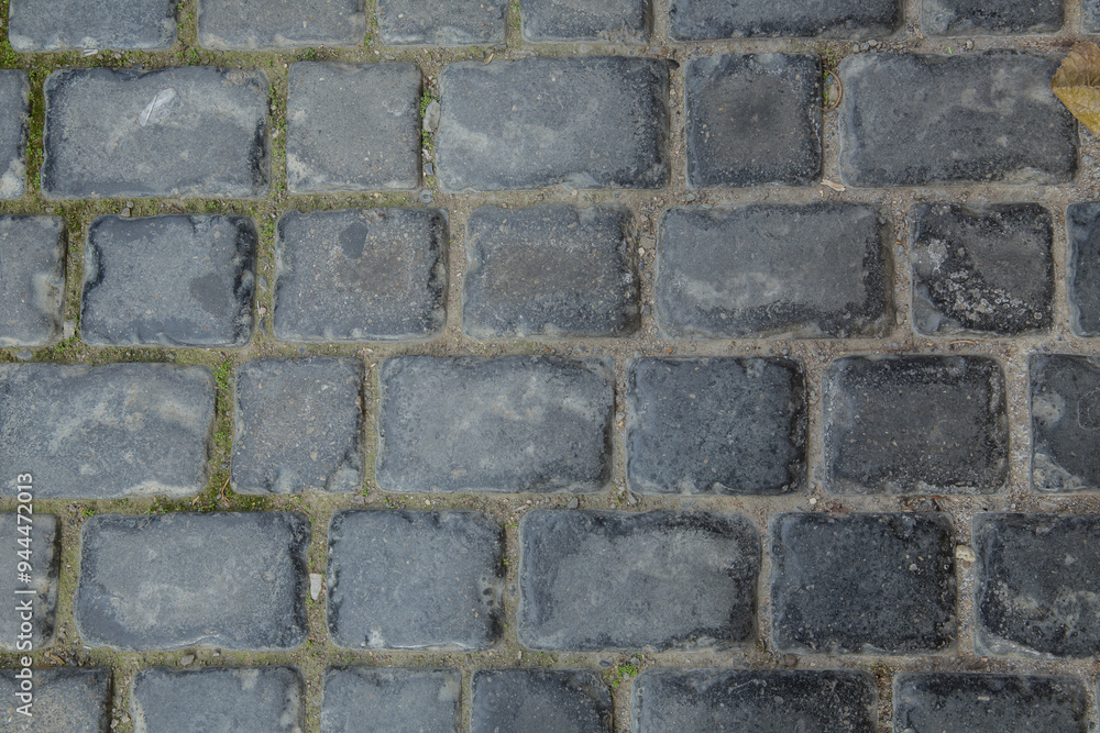 Dark cobble stones . Closeup texture of an old stoneblock pavement cobbled with square granite blocks as an old-fashioned architectural, background . Dark cobble stones . Closeup texture of an old stoneblock pavement cobbled with square granite blocks as an old-fashioned architectural, background .