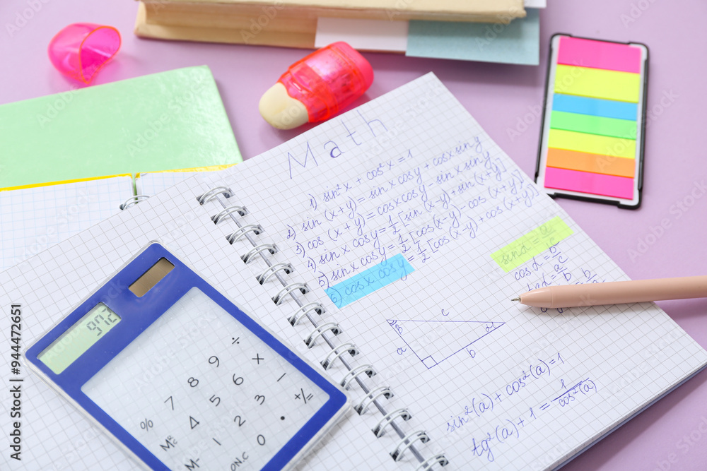 Notebook with calculator and school stationery on lilac background Notebook with calculator and school stationery on lilac background