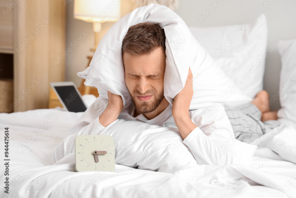 Young man covering head with pillow on bed in bedroom. Insomnia concept Young man covering head with pillow on bed in bedroom. Insomnia concept