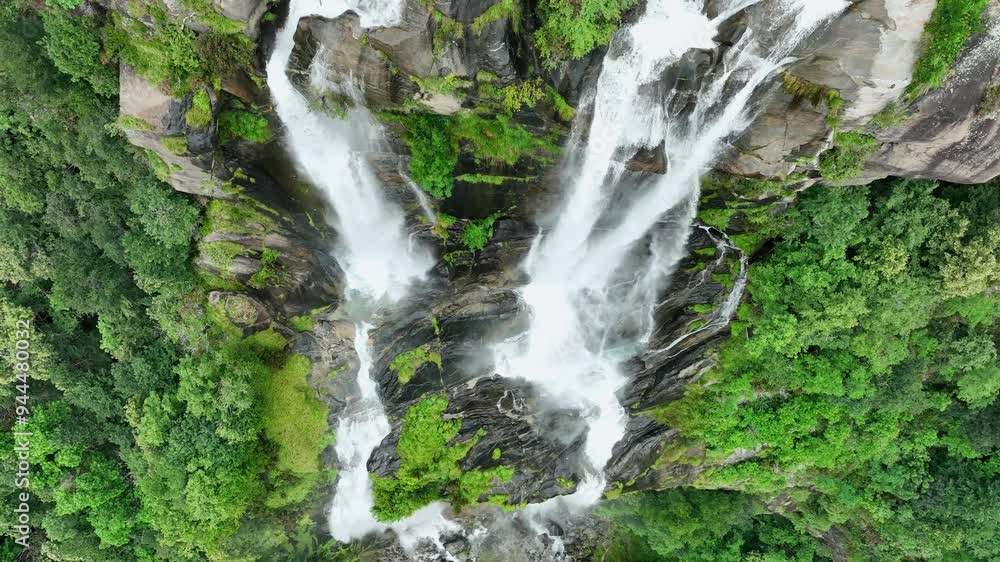 A stunning double waterfall cascades down a lush green mountainside in northern Italy, surrounded by dense forest and misty peaks. The scene captures the raw beauty and serenity of alpine nature. A stunning double waterfall cascades down a lush green mountainside in northern Italy, surrounded by dense forest and misty peaks. The scene captures the raw beauty and serenity of alpine nature.