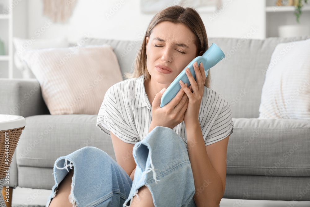 Young woman with hot-water bottle suffering from tooth ache at home Young woman with hot-water bottle suffering from tooth ache at home