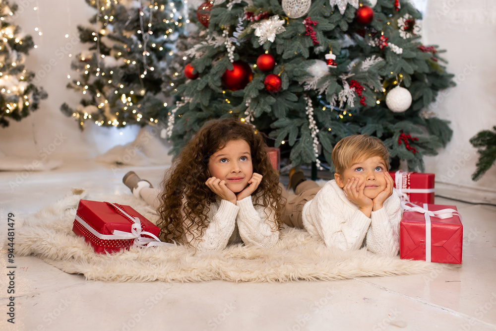 Little children with presents near Christmas tree and lights on background. Merry Christmas and Happy Holidays. Little children with presents near Christmas tree and lights on background. Merry Christmas and Happy Holidays.