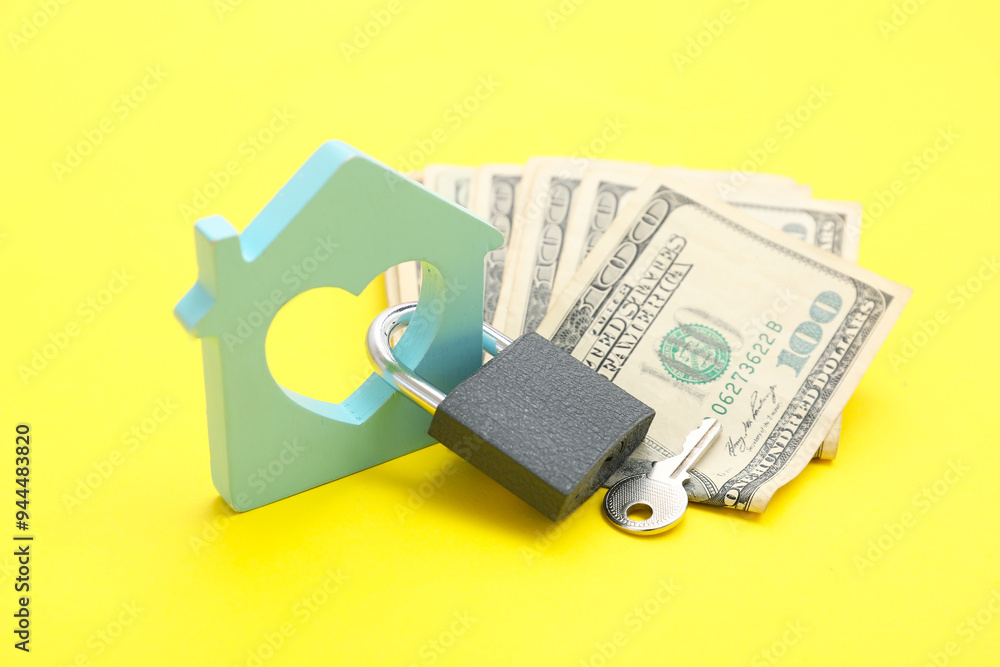 Dollars banknotes with figure of house, padlock and key on yellow background. Concept of buying new house Dollars banknotes with figure of house, padlock and key on yellow background. Concept of buying new house