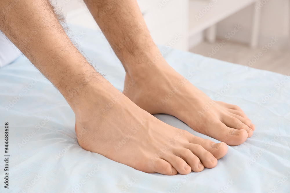 Feet of young man with fresh pedicure sitting on couch in spa salon, closeup Feet of young man with fresh pedicure sitting on couch in spa salon, closeup